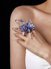 A hand with painted nails and CAMELLIA's adjustable Sagittarius Flower Ring, showcasing a custom flower design, rests gracefully on a shoulder. The intricate floral and beaded patterns highlight exquisite craftsmanship handcrafted in New York.